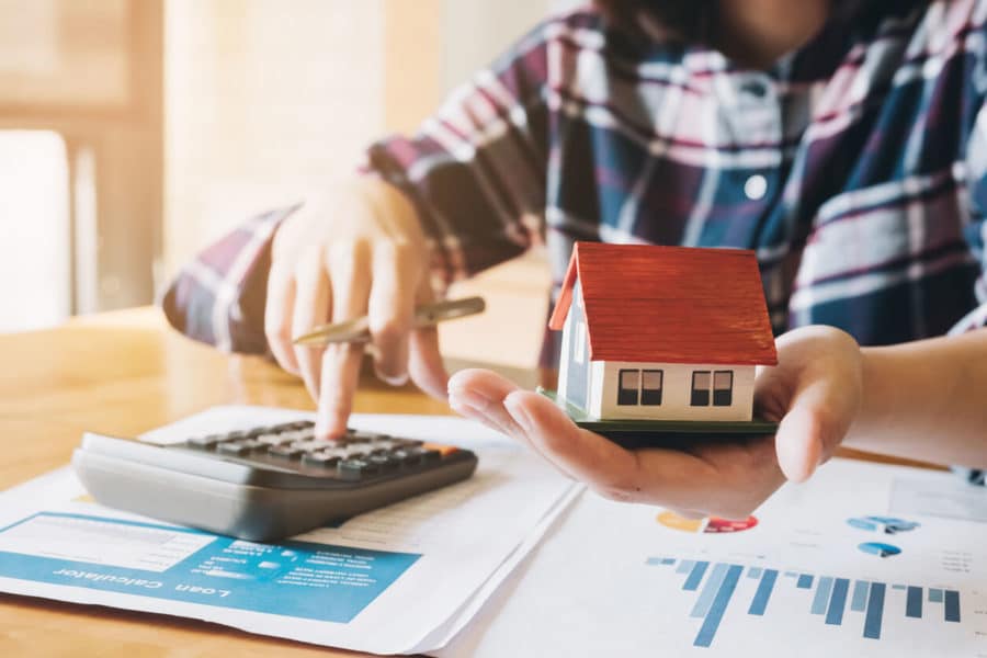 Woman calculating budget before signing real estate project contract with house model at the table in the home stock photo