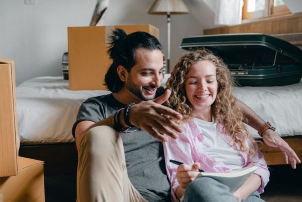 Man and woman sitting beside the bed writing on a notebook