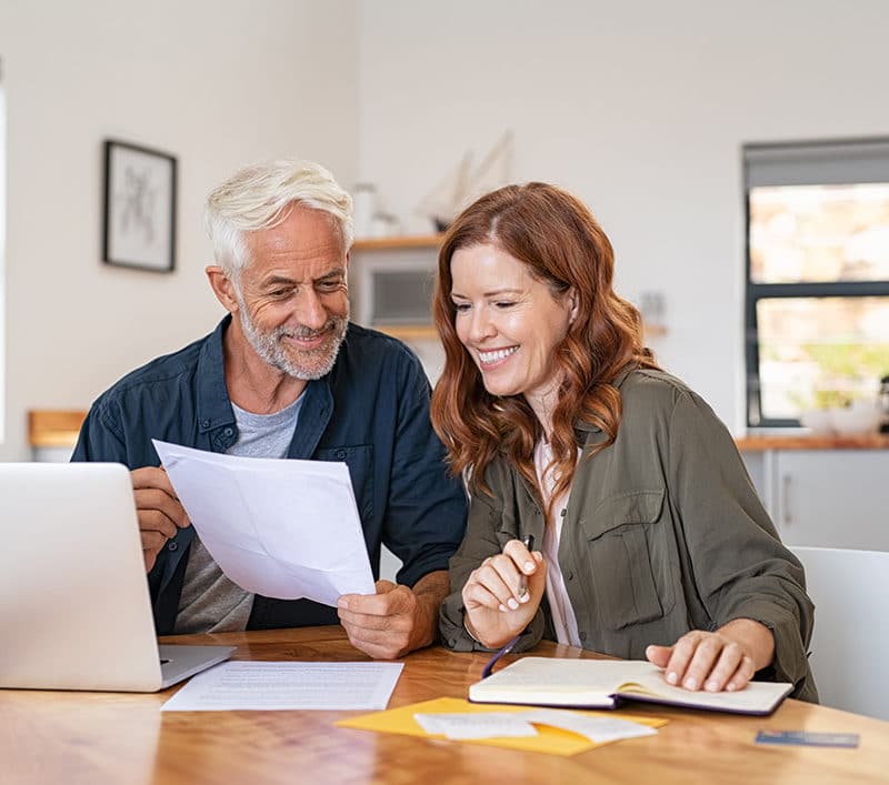 a couple happily reading a paper in front of the dining table