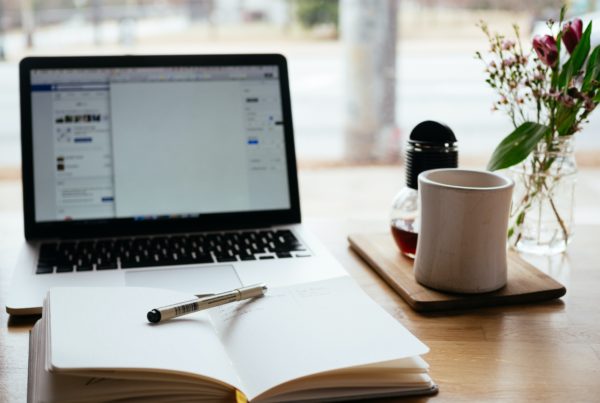 Laptop and note with coffee on the side on table