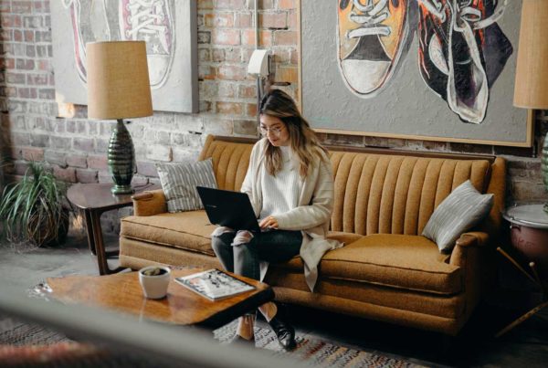 woman sitting on the couch while using her laptop