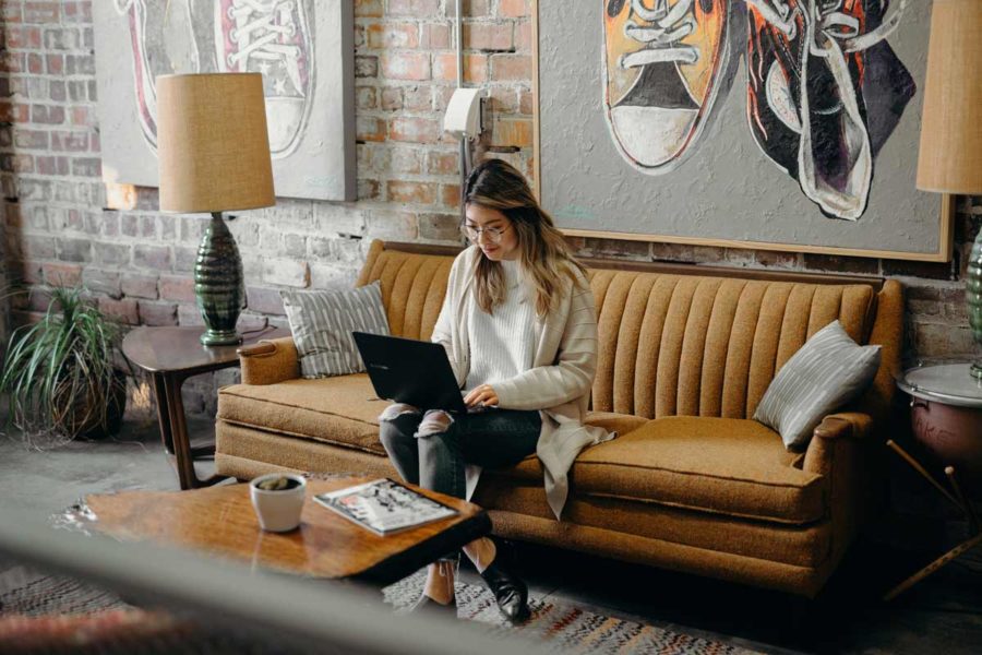 woman sitting on the couch while using her laptop