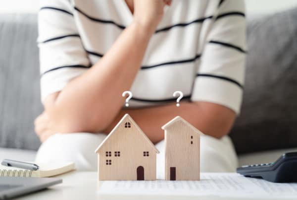 woman is deciding to choose house with Small Wooden House Model with Question Marks, Planning to buy property. Choose what's the best. home loan concepts.