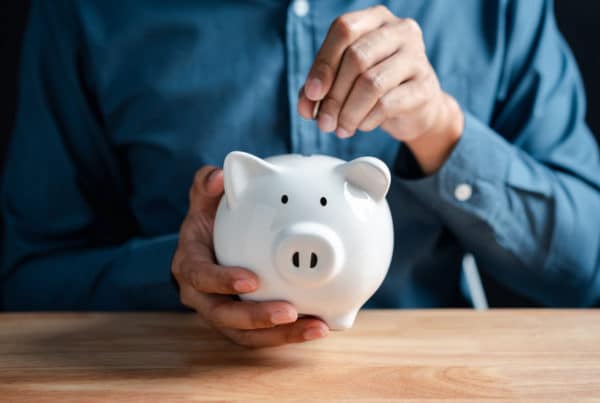 Man putting coin to white piggy bank for deposit banking of investment , retirement planning future saving, invest for profit and interest concept.