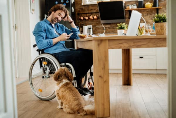 Happy disabled businessman using mobile phone while taking a break from work at home.