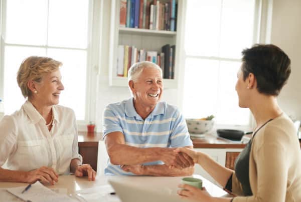 Shot of a senior couple shaking hands with their financial consultant in their kitchen