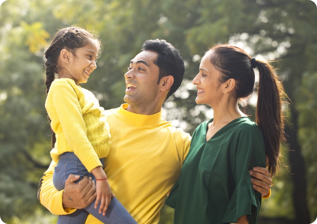 Happy multiracial couple hugging their daughter outdoor.