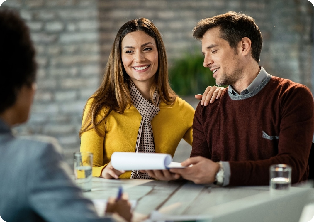 Happy mid adult couple reading documents and communicating with financial advisor in the office