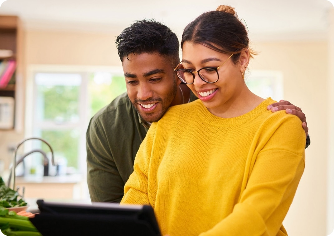 A young couple happy using a digital tablet in their kitchen