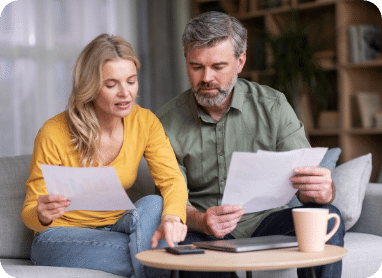 Busy middle aged husband and wife calculating family budget together.