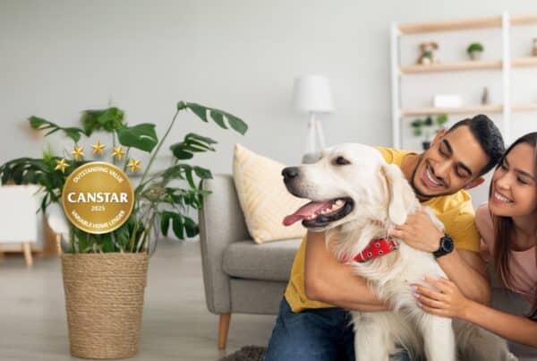 Happy multiracial couple hugging their golden retriever in living room, sitting on floor at home.