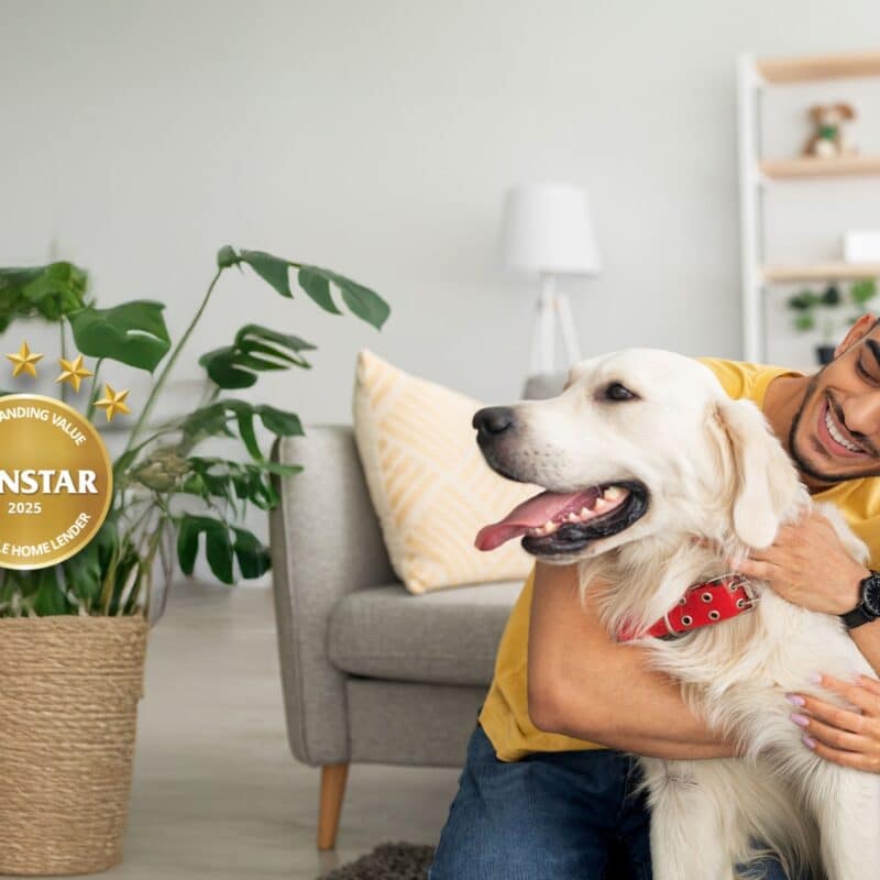 Happy multiracial couple hugging their golden retriever in living room, sitting on floor at home.